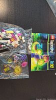 View of two sealed plastic bags containing assorted Lego bricks and parts next to colorful instruction manual