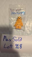 Front view of the Jake The Dog Lego minifigure sealed in plastic bag with handwritten label