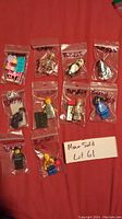 Photo of all 10 Lego Movie minifigures in individual labeled plastic bags on red fabric.