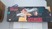 Top view of the original Super Nintendo Super Scope box showing front artwork and branding with boy holding the Super Scope light gun.