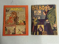 Two comic books, one with orange back cover showing Capt. Marvel and tiger, the other with front cover titled 'Balbo The Boy Magician' in worn condition.