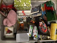 Overview of bin showing various items including pink flamingo figurine, decorative boxes, model toys, and framed collectibles.