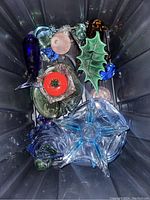 Photo showing the entire lot of colorful glass pieces including various shapes and colors inside a plastic bin.