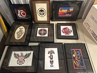 Full overview of all nine framed Indigenous art prints arranged on floor, showing various sizes and distinctive traditional styles and colors.