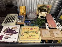 Overview of all kitchen items showing knife set, cheese tools, glass baking dish, Whitman's sampler tin, kitchen timer, lock guard, placemats, and other accessories.