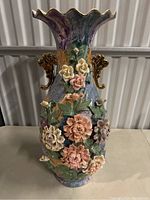 Front view of the large floral vase showing colorful patchwork design, 3D flowers, and gold-tone handles.