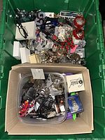 Top view of green bin filled with a variety of bracelets, earrings, and other jewelry items.