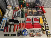 Full view of mixed tools and packing materials including gloves, gardening tools, paintbrushes, scissors, measuring tape, and twine.