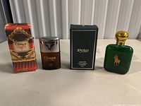 Two vintage Ralph Lauren cologne bottles with their original boxes displayed side by side: Polo 120 ml green glass bottle with gold cap on right, Chaps 55 ml brown bottle with silver cap on left.