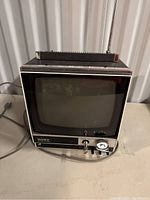 Front view of compact Sony Solid State black and silver vintage TV with protruding antenna and control knobs.