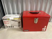 Photo shows boxed Philips toaster and red International metal toolbox side by side.