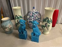 Full lot showing five vases and two turquoise guardian lion statues on a tabletop.