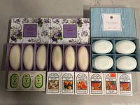 Photo showing two floral Hatfield & Hodges English Country Garden Lavender soap boxes, one open with 3 oval lavender soaps visible, Smithian Stevens Lemon Verbena set box with 4 white soaps, and 8 unopened Alpen SOAP bars in various vintage designs.