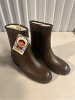 Front and side view of women's brown leather boots showing the shearling interior and side zipper.