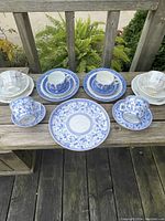 Tea cups and saucers arranged on bench showing blue and white patterns and floral white pieces
