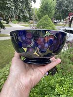Photo of the outside side view of the cobalt blue pottery bowl with floral Jacobean pattern showing grapes and leaves.