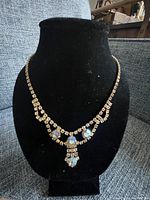 Full view of the vintage gold-tone lavaliere necklace displayed on a black velvet bust, showing the 18 inch length and overall design with sparkly rhinestones and larger iridescent stones at the center pendant section.