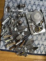 Top-down image showing the full assortment of cutlery and serving pieces spread on a textile mat.
