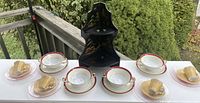Full lot showing chinoiserie corner shelf, four demi cups and saucers, and four bouillon bowls arranged in a row.