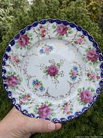 Front view showing the floral and gold detail with blue scalloped rim.