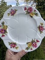 Front view of Shelley fine china 9.25 inch dinner plate showing white porcelain with pink and yellow begonia flower motifs and scalloped edges.
