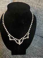 Full view of the vintage rhinestone lavaliere necklace displayed on a black necklace stand.