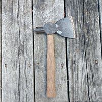 Tomahawk axe laid flat on wooden surface showing the full length and shape from above.
