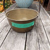 Front view of the solid brass pot showing the outer surface with a green label 'Solid Brass' attached.