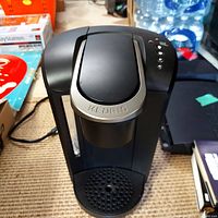 Black and silver Keurig coffee maker with control buttons and drip tray visible.