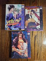 Front cover view of three manga volumes: Yellow Omnibus Edition Vol. 2, Hayate no Gotoku 3, Vampire Knight 3, arranged on wooden surface.
