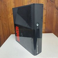 Side angled view of black Xbox 360 console with red 'Switch' decal on the side.
