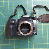 Minolta Maxxum 3000i 35mm film camera body front view without lens showing lens mount and mirror. Neck strap visible.