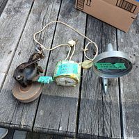 Three vintage items on wooden surface: a car mirror, Bakelite clock with cord, and hand grinder.