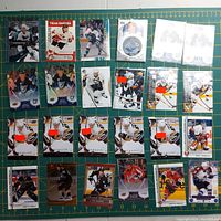 Wide shot of a collection of NHL hockey cards arranged on a green cutting mat showing various players and teams including Sidney Crosby and team Canada cards.