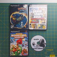 Front cover of three PlayStation 2 games and one PlayStation 3 game disc. Shows Ratchet & Clank: Going Commando, Grand Theft Auto: Vice City, Super Monkey Ball Adventure in cases, and Skate PS3 game disc loose.
