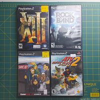 Front covers of four PlayStation 2 games XIII, Rock Band, Scooby-Doo! Save 10%, and ATV Offroad Fury 2 laid out on a table.