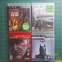 Front view of the four PS3 game cases showing cover art: The Walking Dead Game of the Year Edition, The Walking Dead Season Two, Metal Gear Solid 4 Greatest Hits, Batman Arkham Asylum.