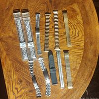 All twelve watch bands laid out on wooden surface showing both boxed and loose items