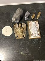 Top view of six decorative figurines including three angels and three animals on black surface.