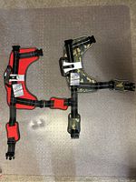 Two dog harnesses laid flat, one red size 3XL and one camouflage size 2XL, both with tags