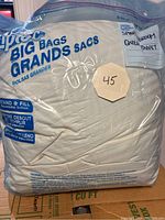 Photo showing the queen duvet insert packed inside a large clear zipper bag labeled 'BIG BAGS BRANDS SACS' with an octagonal beige tag marked '45'