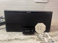 Front view of black Sony speaker dock with 30-pin connector for iPhone/iPad on a granite countertop.