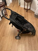 Front side view of black City Mini Baby Jogger stroller with padded seat and handlebar showing three wheels.