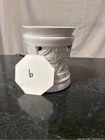 Full view of the white ceramic wax melt warmer showing floral cutout patterns around the body with high-gloss finish.