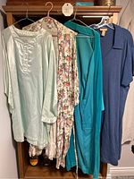 Four robes and a nightie hanging on hangers showing color and fabric details
