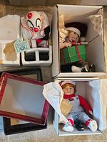 Clown doll in styrofoam packaging with DoA Dynasty Doll tag, lacking outer box; two boy dolls boxed, one holding gift box, one in striped overalls.