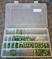 Clear plastic container with multiple compartments holding green turquoise beads in various shapes and sizes, including round, oval, and irregular beads with characteristic veining.