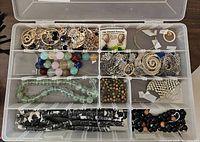 Top view of entire container showing compartments filled with various jewelry and beads.