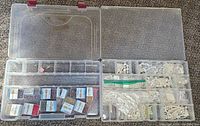 Top view of two plastic storage containers open showing compartments filled with multiple jewelry making items including seed beads and pearl-like beads.