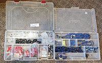 Top open view of two plastic storage containers with assorted carved and polished bead strands, charms and pendants of white crystal, jasper, rose quartz, and lapis lazuli stones.